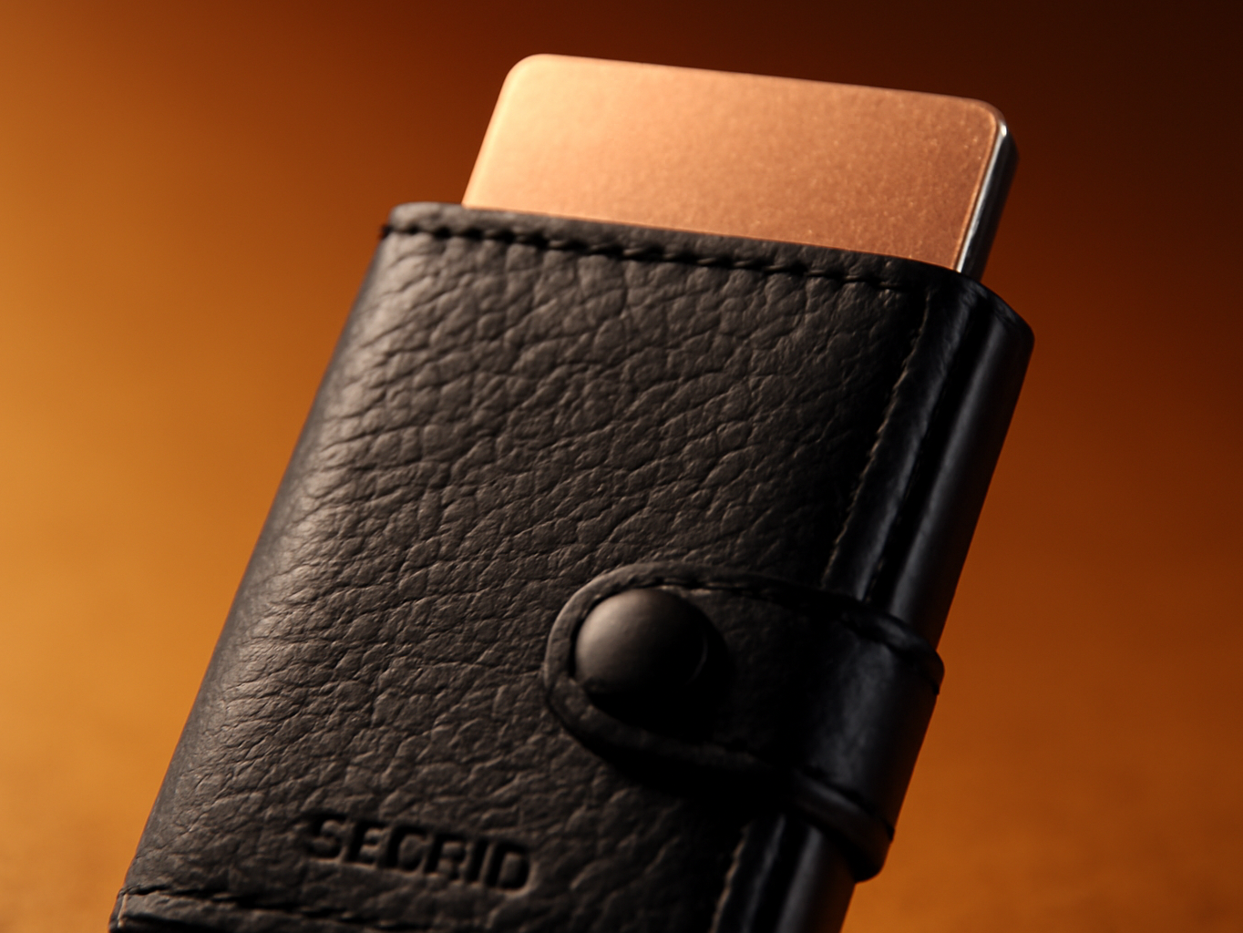 Close-up of leather wallet's pop-up button mechanism with card partially ejecting from slot
